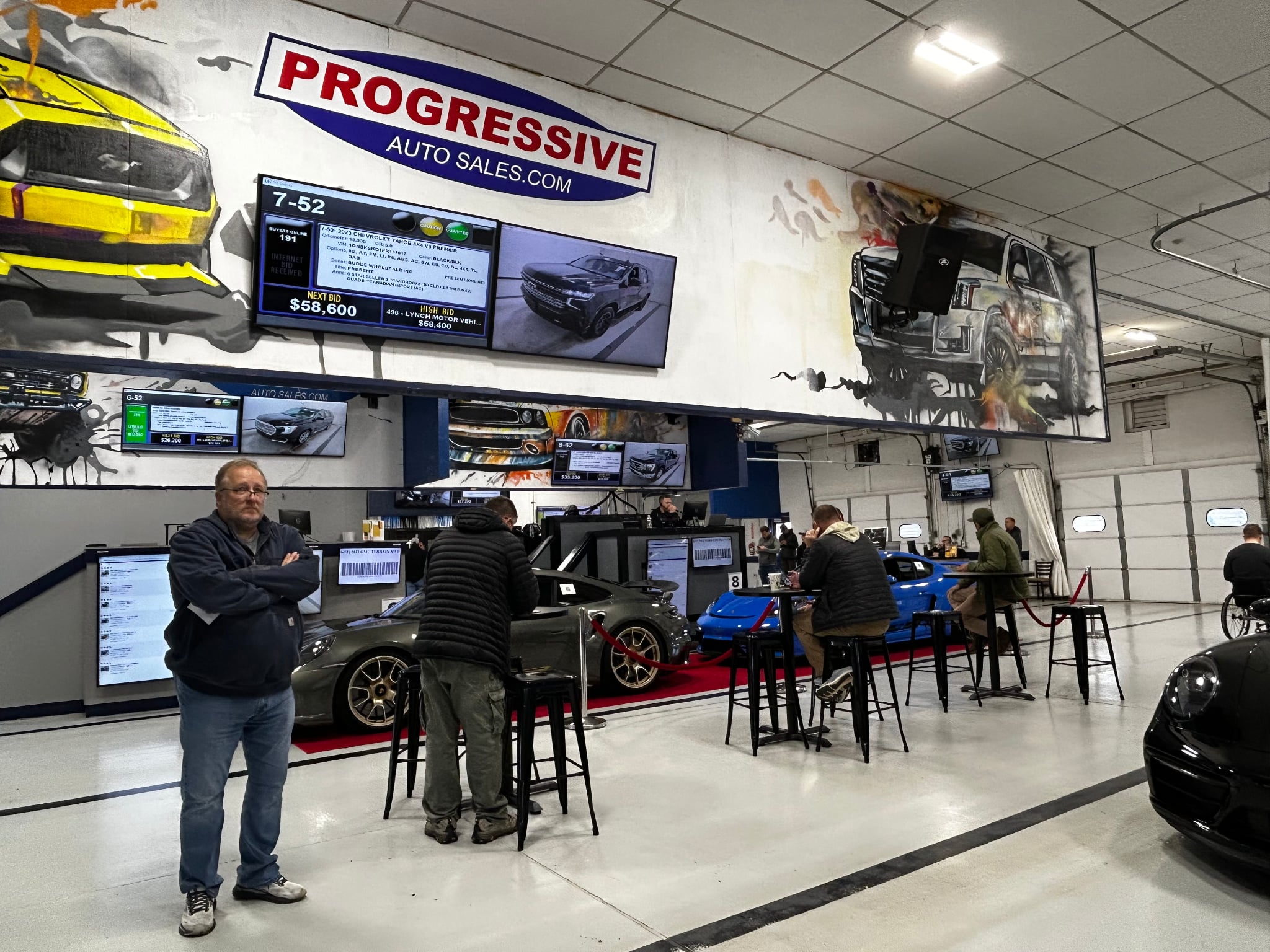 Porsche 911 and blue Porsche Cayman staged on the live auction lane floor